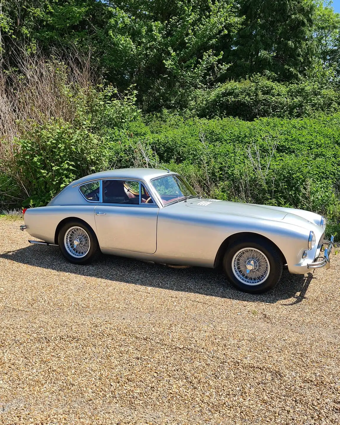 Silver classic coupé on a gravel drive
