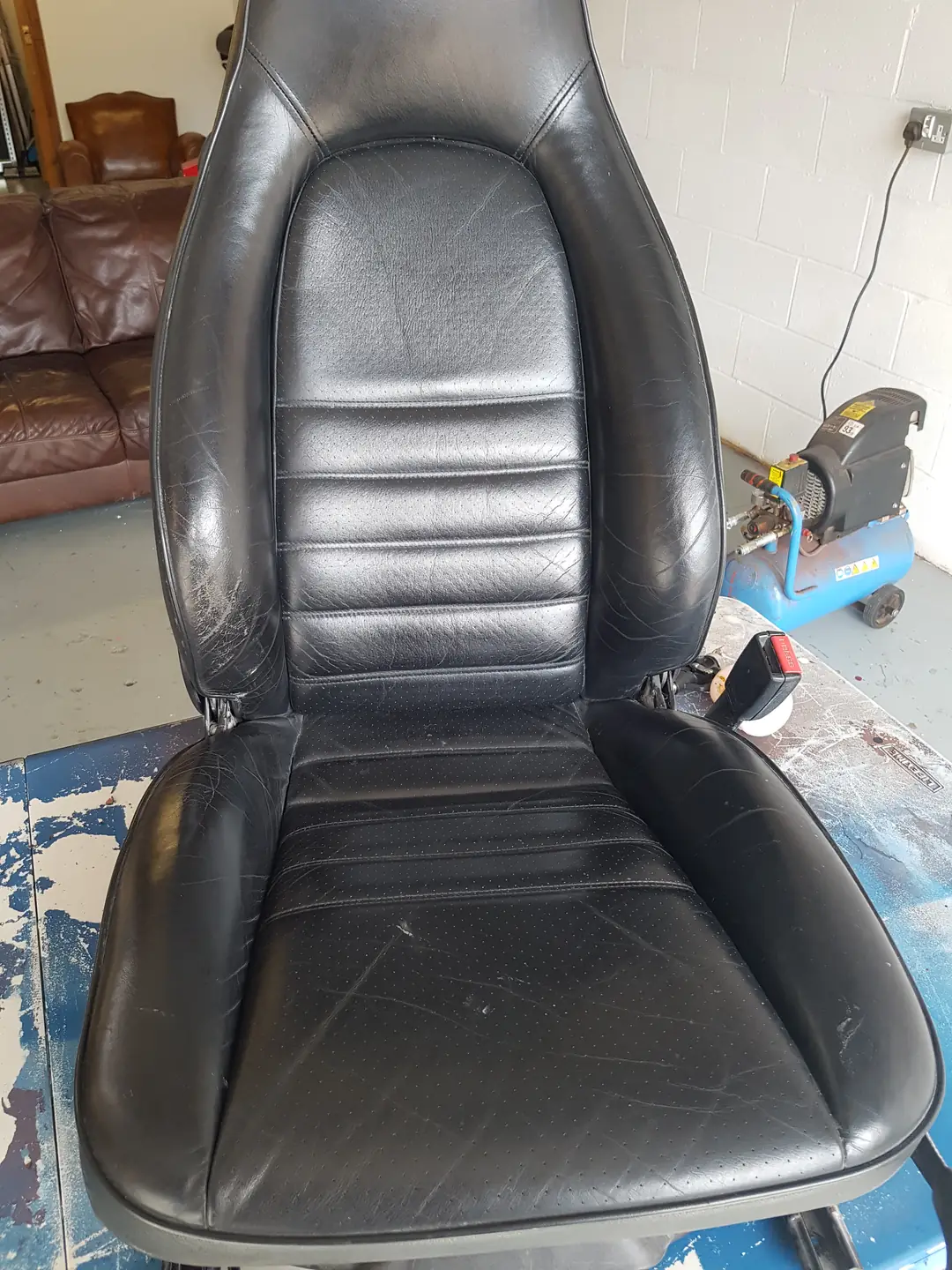 Worn black leather sports seat before restoration
